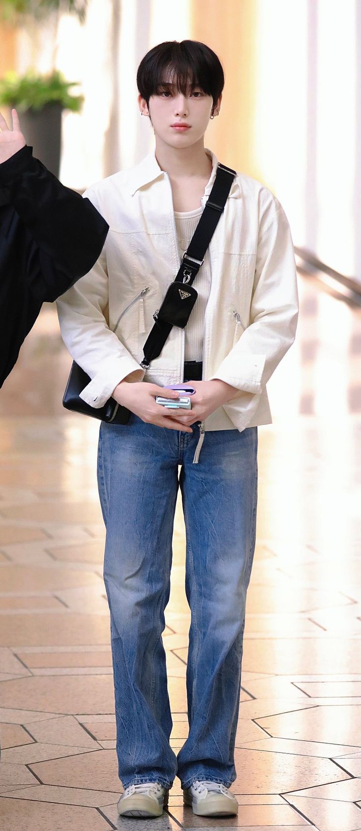 a young man is standing on the sidewalk