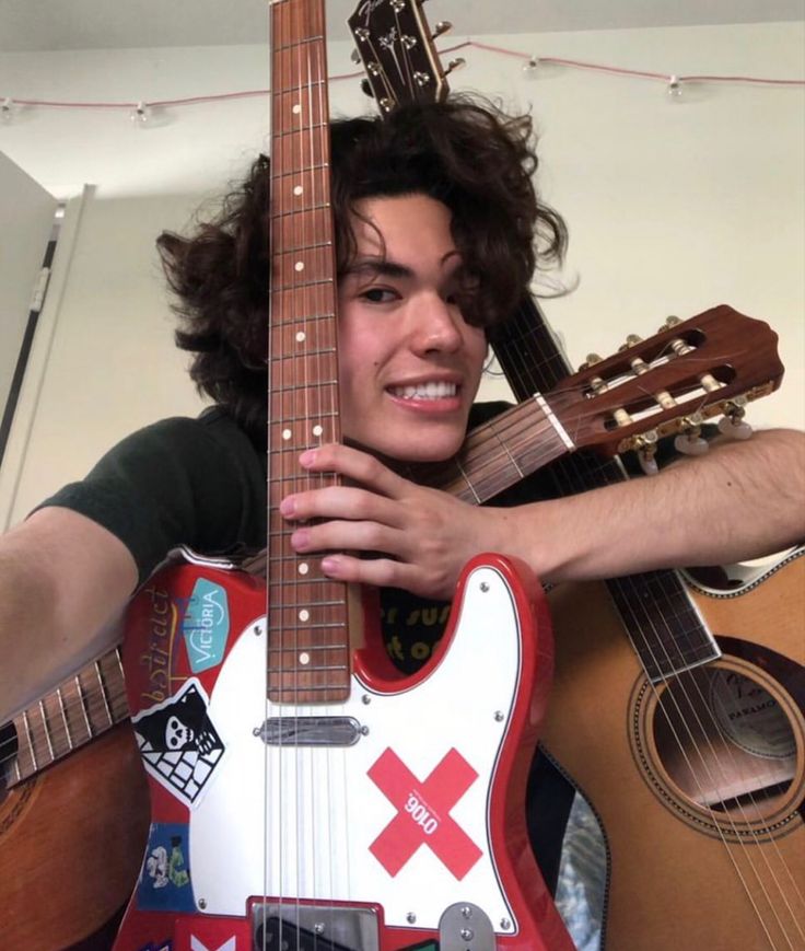 a man is holding an electric guitar and posing for the camera with it's neck propped up