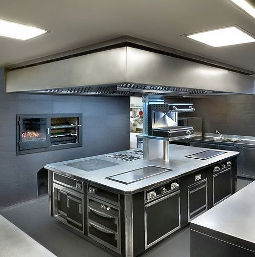 a large kitchen with an oven, stove and counter tops in front of the fireplace