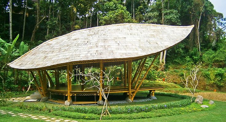 a gazebo in the middle of a lush green area with trees and bushes around it