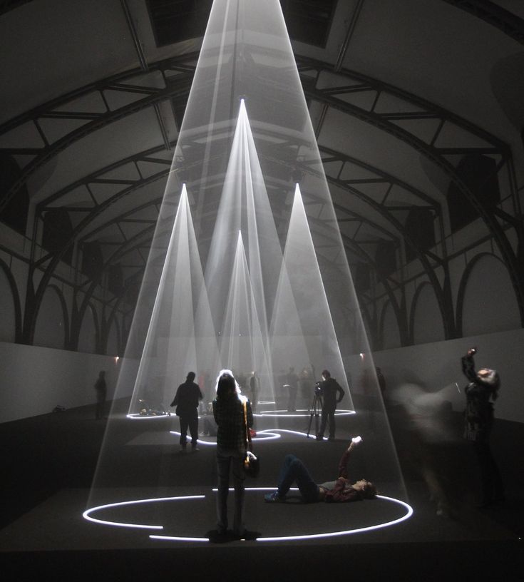 people are standing in the middle of a room with white light streaming from it's ceiling