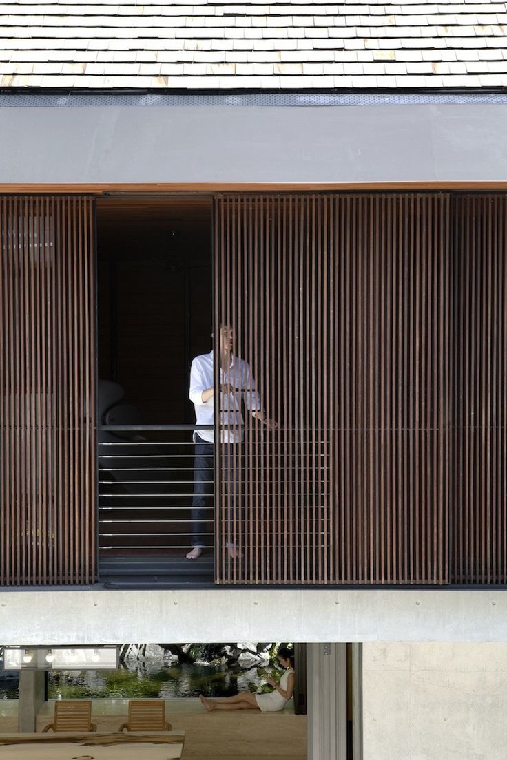 a person standing on a balcony next to a building with wooden slatted doors