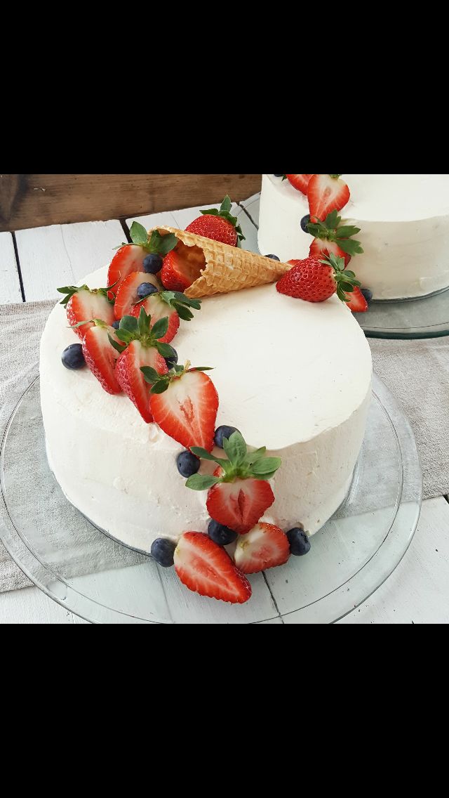 two cakes with strawberries and blueberries on top