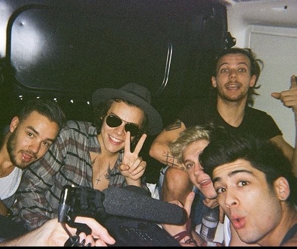 a group of young men taking a selfie in the back of a van with their cell phones