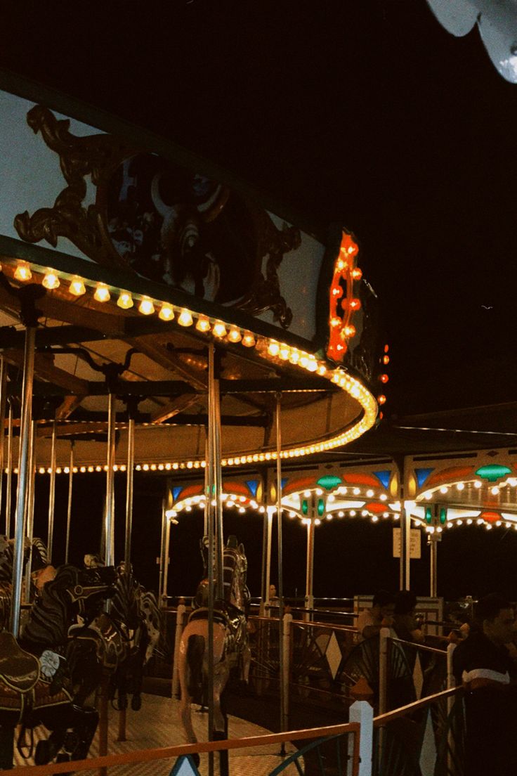 an amusement park at night with people on the carousel