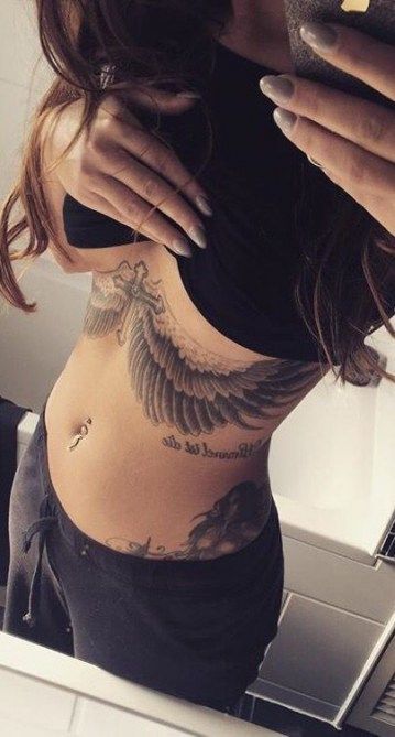 a woman with tattoos on her stomach looking at her cell phone and holding a smart phone