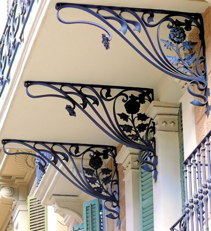 an iron balcony railing with blue shutters and flowers on it