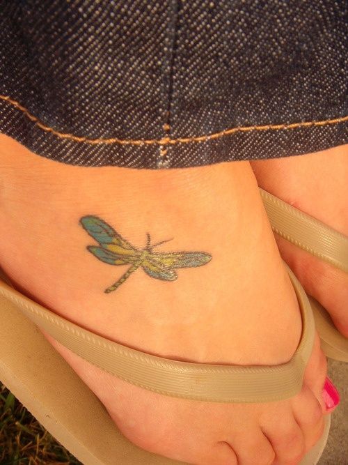 a woman's foot with a dragonfly tattoo on it