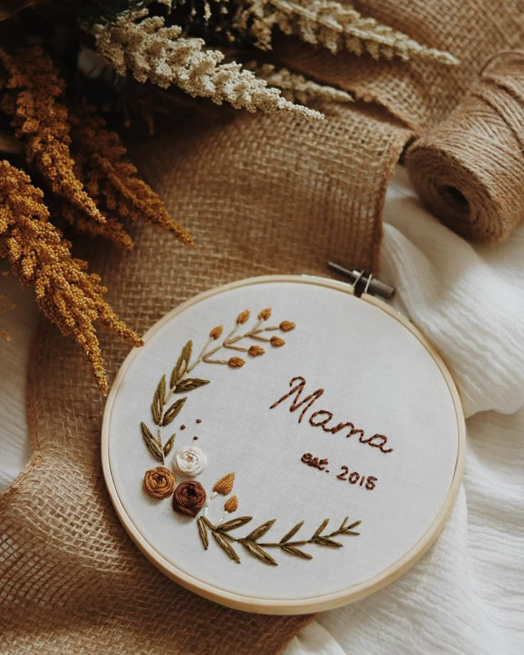 a close up of a embroidery on a piece of cloth next to some flowers and twine