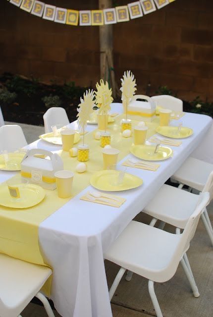 a table set up with yellow plates and napkins for an outdoor party or gathering