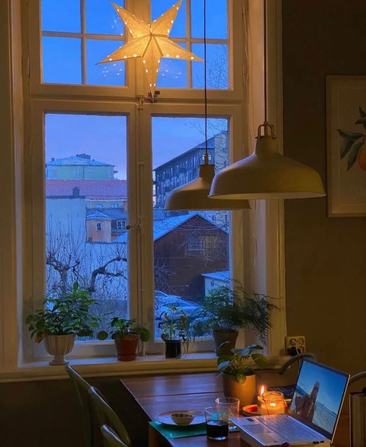 a laptop computer sitting on top of a wooden table in front of a large window