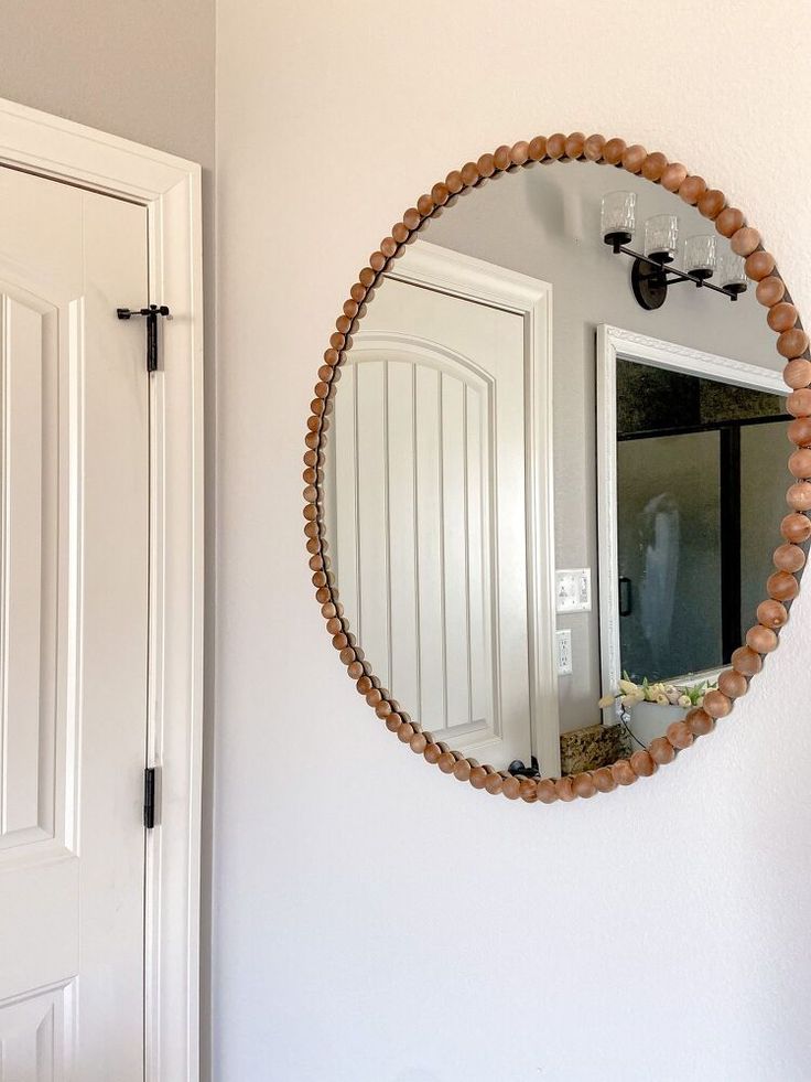 a round mirror hanging on the wall next to a white door with a black handle