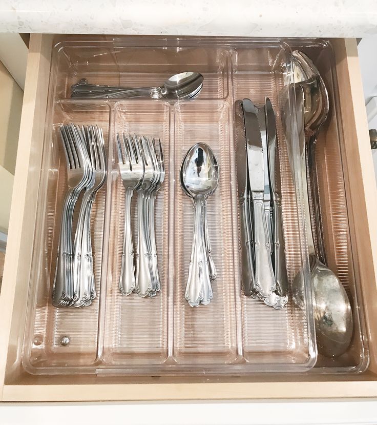 an open drawer with silverware and spoons in it, including forks and knives