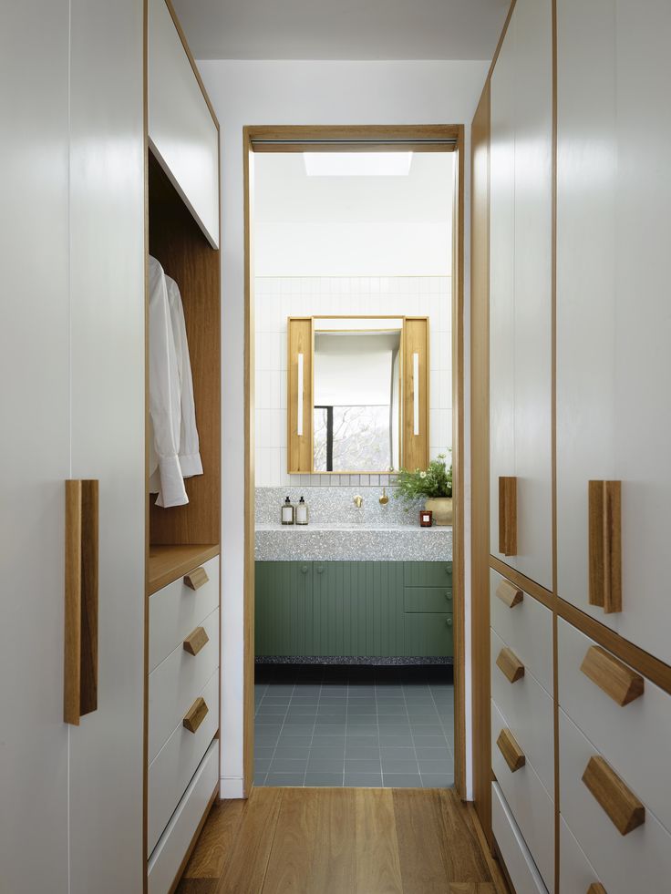 an open door leading to a bathroom with white walls and green cabinetry on both sides