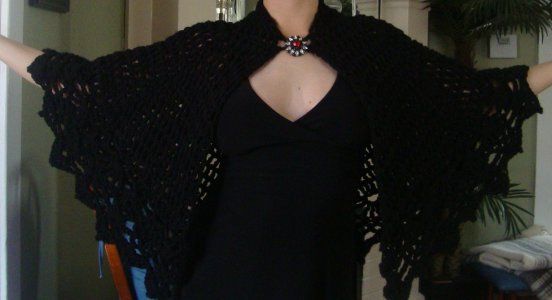 a woman in a black dress is wearing a shawl