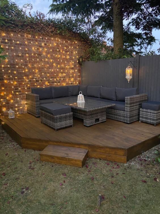 an outdoor seating area with lights on the wall and wooden steps leading up to it