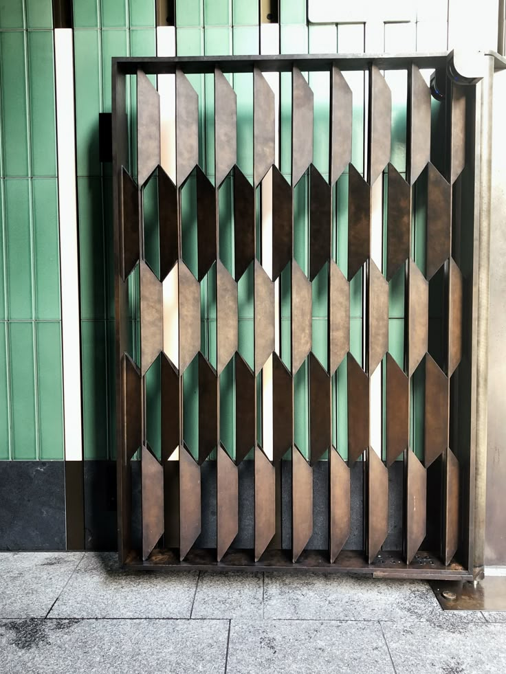 a metal gate that is on the side of a building next to a wall with green tiles