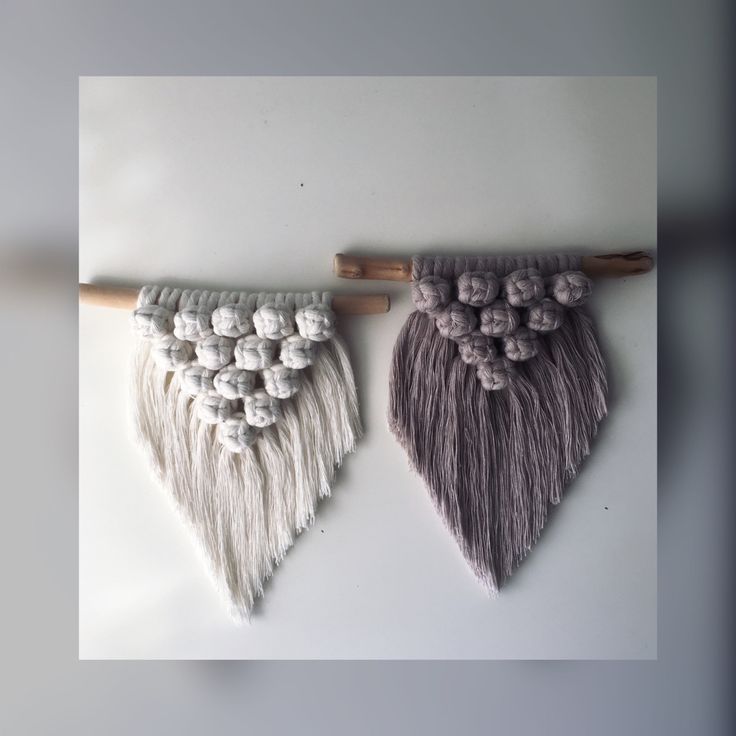 two pieces of yarn hanging on a wall with wooden sticks and balls attached to them