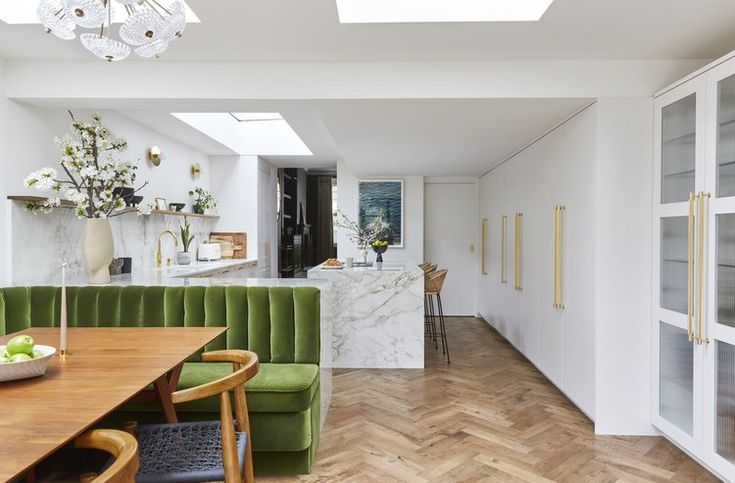 a green couch sitting in the middle of a room next to a wooden dining table