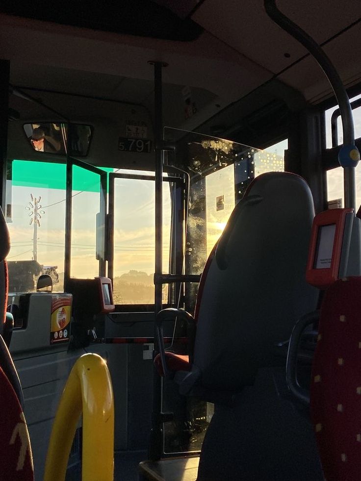 the inside of a bus with two people sitting on it's seats and one person standing at the back