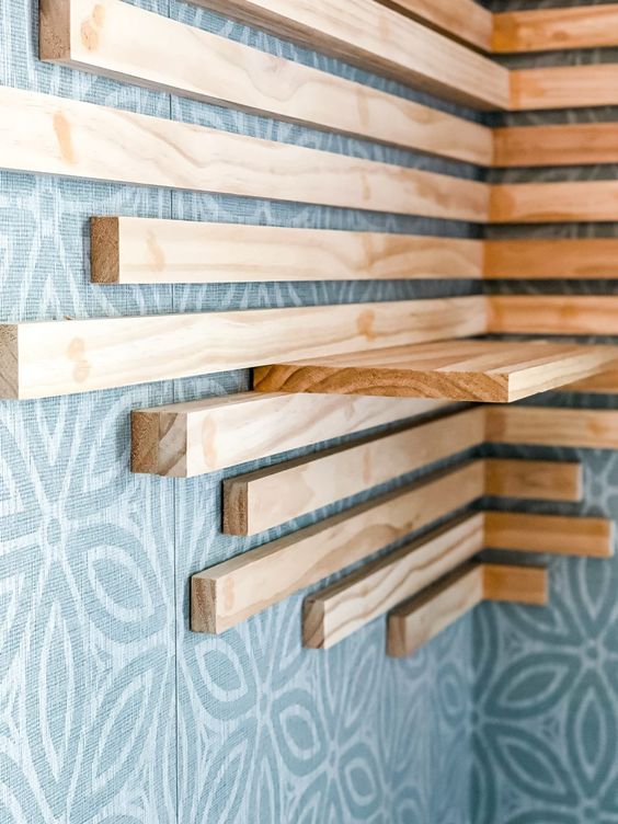 a wooden shelf mounted to the side of a wall next to a blue patterned wall