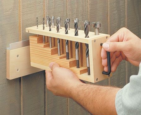 a man is holding a tool holder with many tools in it and he is working on the wall