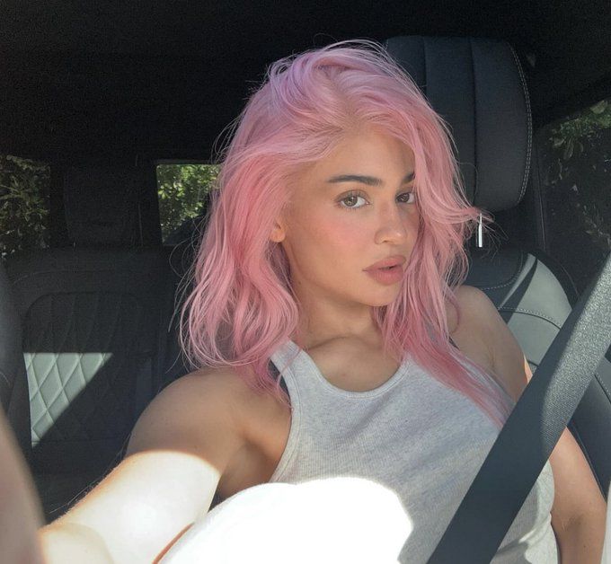 a woman with pink hair sitting in a car