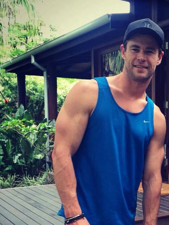 a man in a blue shirt and hat standing on a wooden deck next to a building