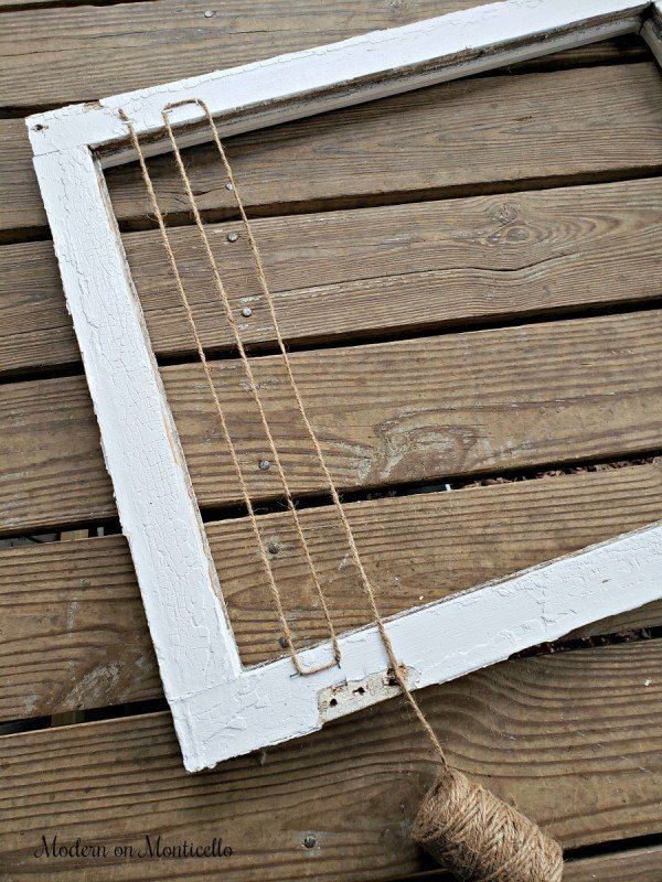 an old window frame with twine and rope hanging from it on a wooden floor