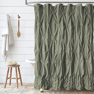 a green shower curtain in a bathroom with wood floors and white walls, along with a wooden stool