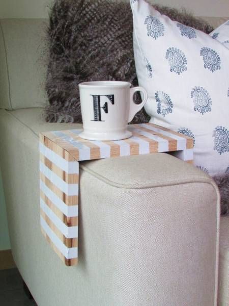 a coffee cup sitting on top of a wooden table next to a white and brown ottoman