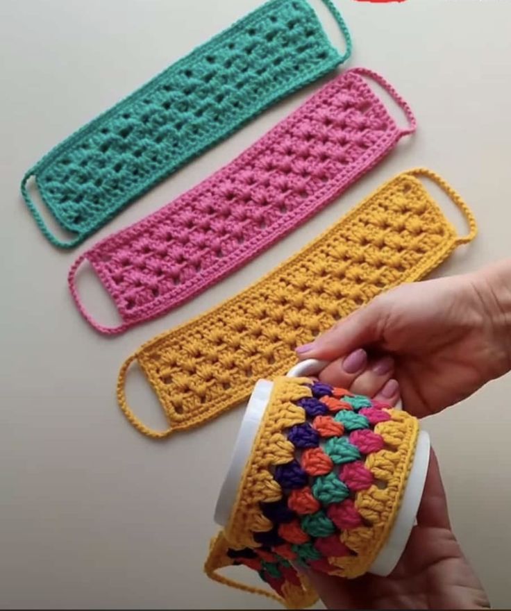 three crocheted washcloths are being held up by someone's hand