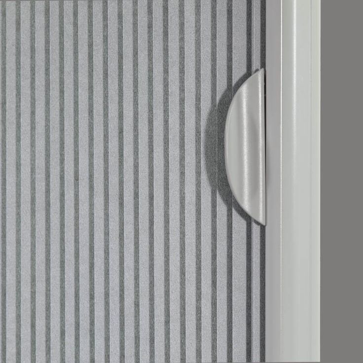 a close up of a door handle on a striped wallpapered room with vertical blinds