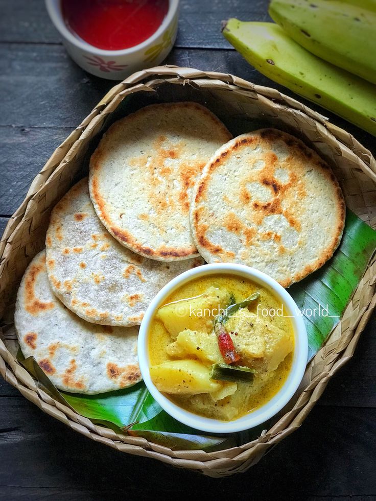 a basket filled with pita bread next to a bowl of soup and two bananas