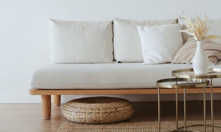 a white couch sitting on top of a wooden floor next to a table with two side tables