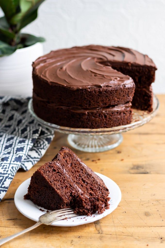 a piece of chocolate cake on a plate with a fork in front of the cake