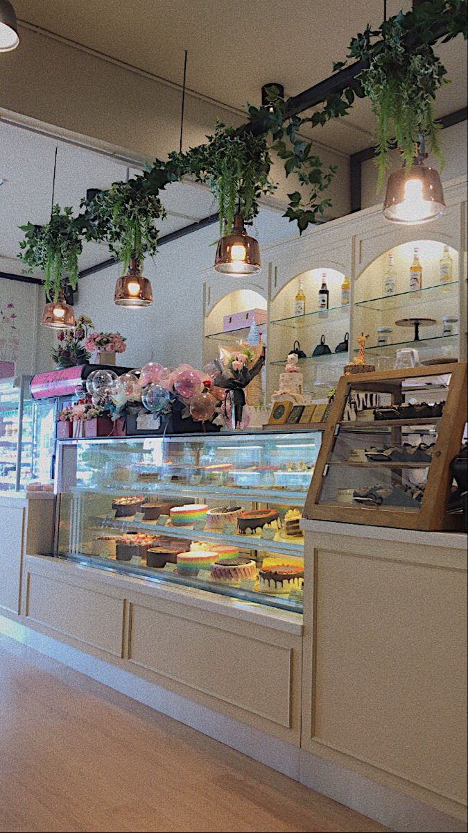 the inside of a bakery filled with lots of cakes and pastries under hanging lights