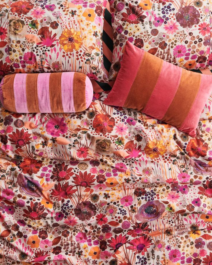 an image of a bed with flowers and stripes on the comforter cover, along with two pillows