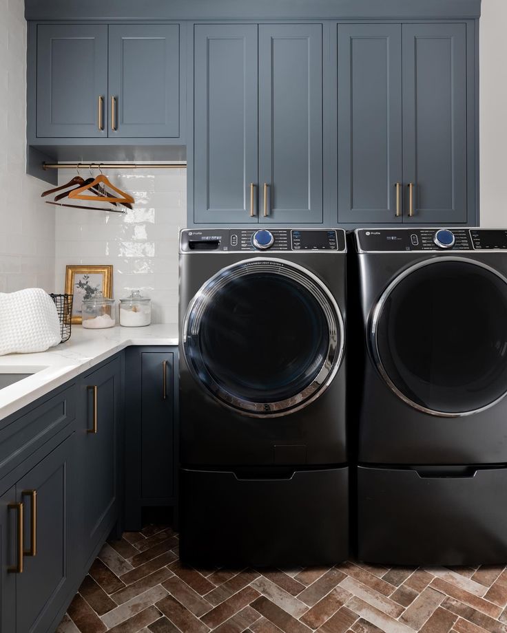 a washer and dryer in a kitchen with blue cabinets on either side of the washer