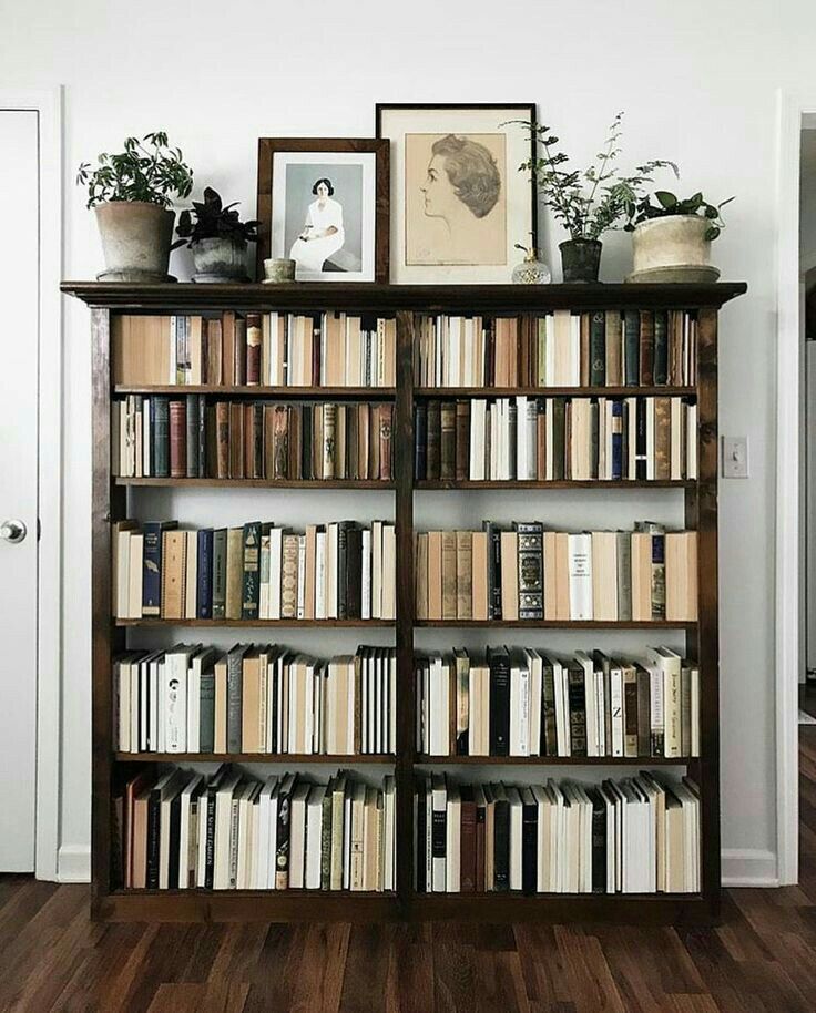 a bookshelf filled with lots of books on top of wooden floors next to a doorway