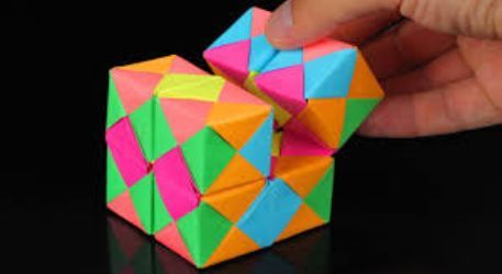 a hand is holding an origami cube