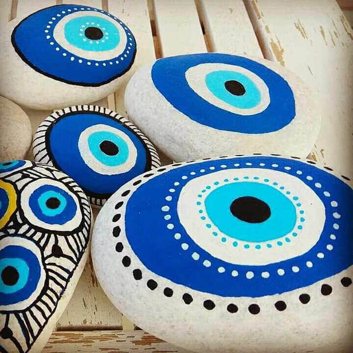 several painted rocks sitting on top of a wooden table with blue and white circles in the middle