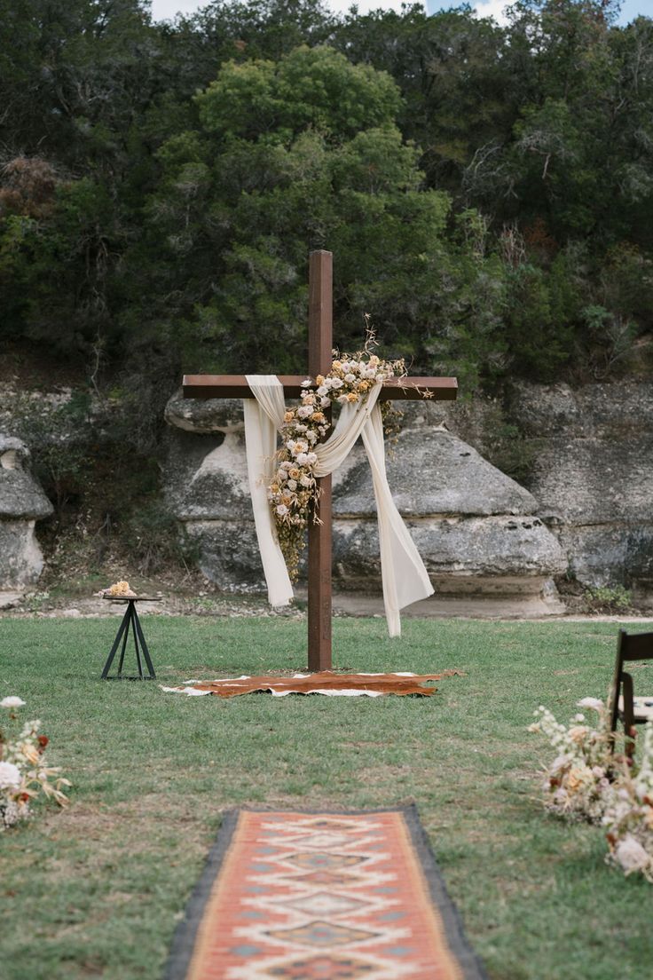 a wooden cross sitting on top of a lush green field