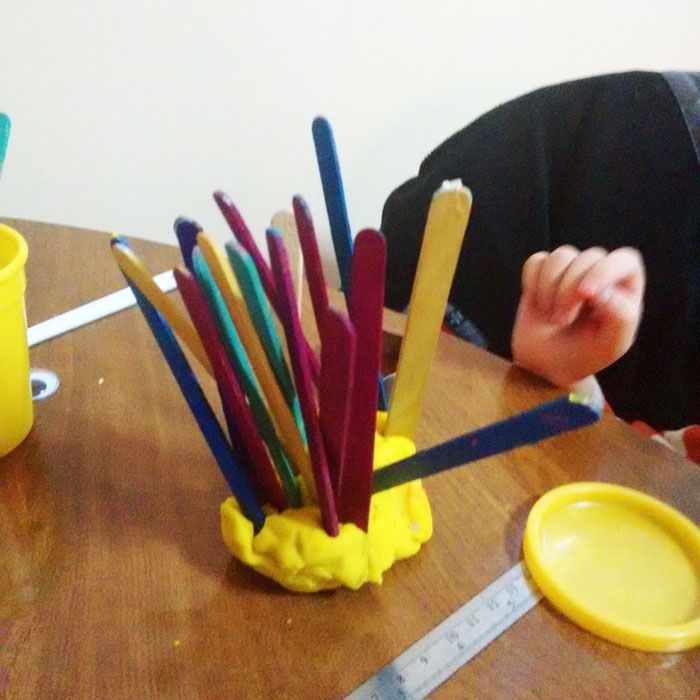 a child is sitting at a table with pencils in a cup