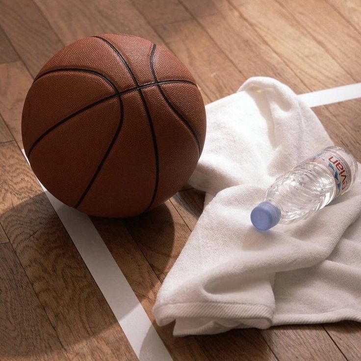 a basketball sitting on top of a wooden floor next to a white t - shirt