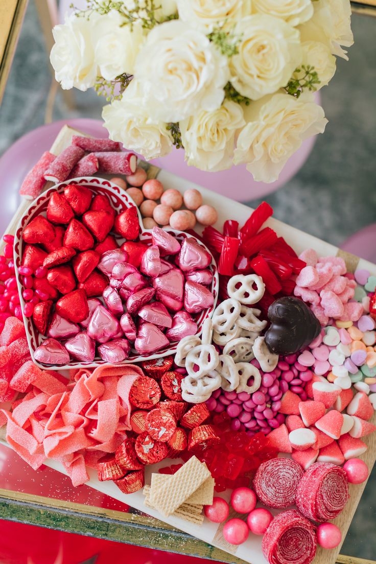 valentine's day treats arranged in a heart shaped box on a table with flowers