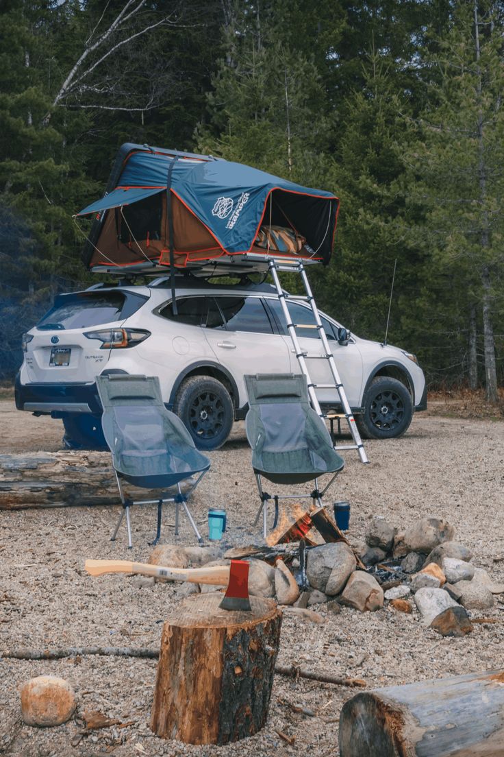 a car is parked next to a camp site with two chairs and a tent on top