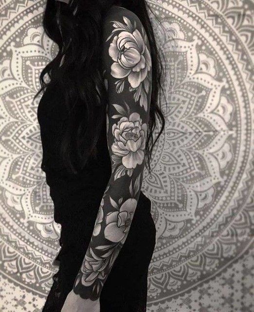 a woman with long black hair and tattoos on her arm