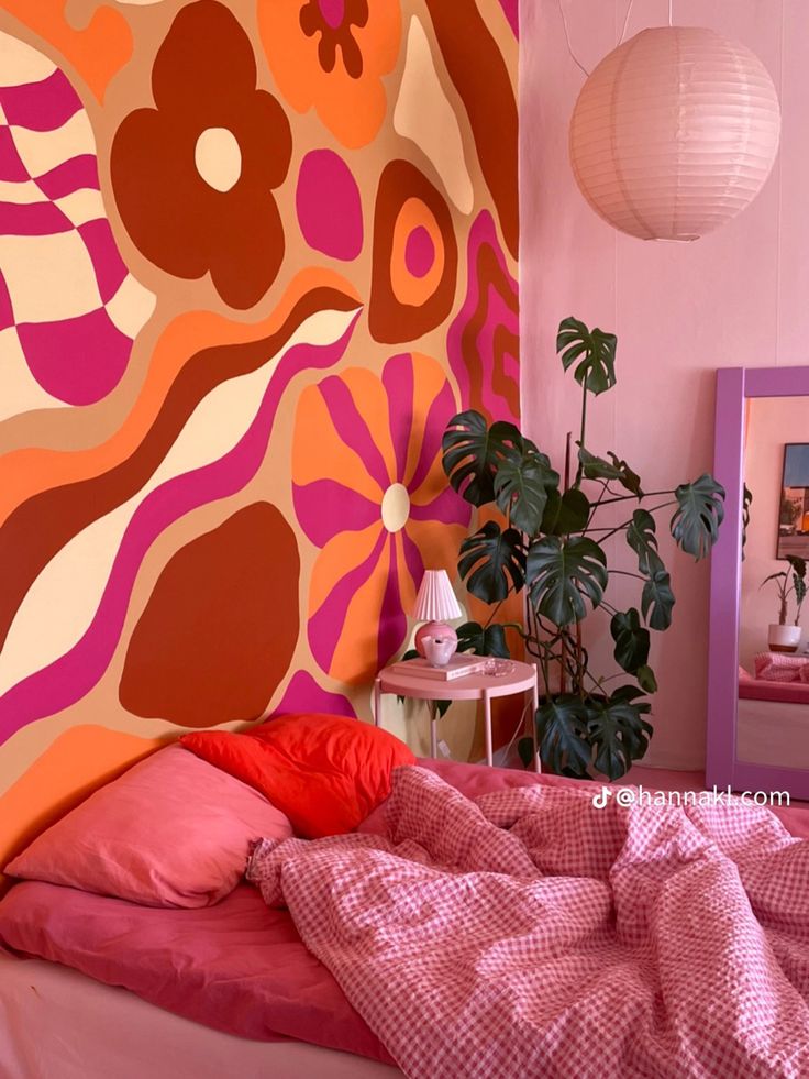 a bedroom decorated in pink, orange and red with a large painting on the wall