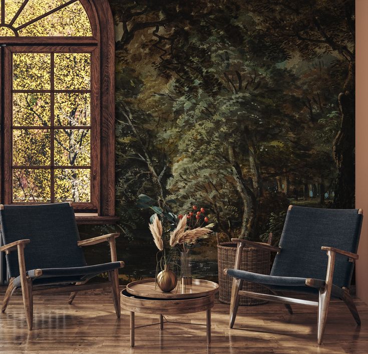 two chairs and a table in front of a window with a painting on the wall